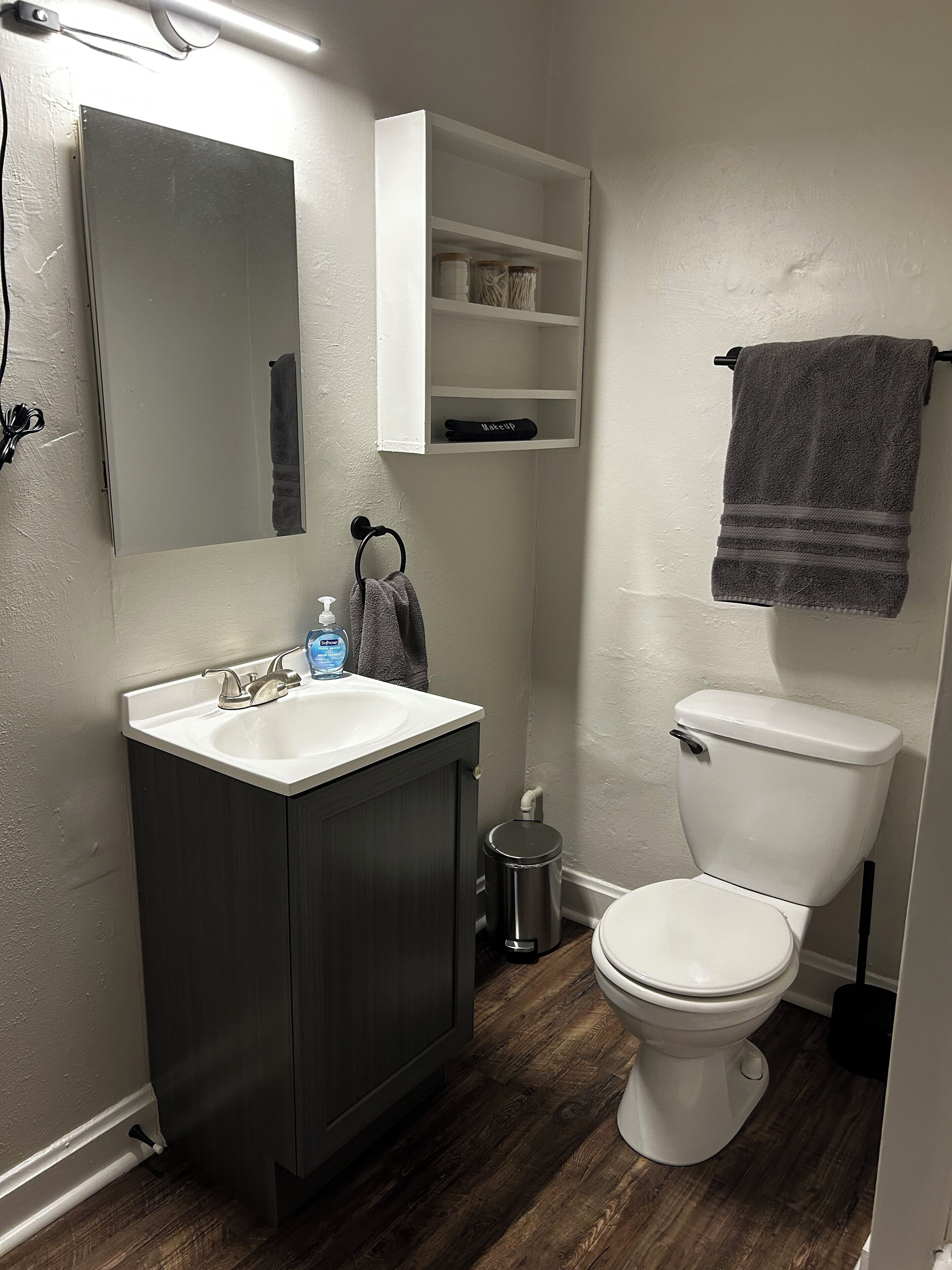 Een badkamer met een wit wastafel, een donker houten kast, een wit toilet en een handdoek aan een rek.