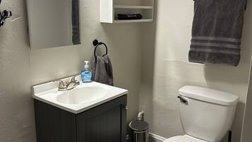 Een badkamer met een wit wastafel, een donker houten kast, een wit toilet en een handdoek aan een rek.
