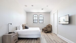 A bedroom with a bed, a dresser, a chair, a window, and a wall-mounted TV. - 5-Bedroom Villa in Reunion Resort, Orlando Villa 6415 (Orlando)