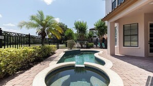 A swimming pool with a curved design, surrounded by a brick walkway and lush greenery. - 5-Bedroom Villa in Reunion Resort, Orlando Villa 6415 (Orlando)