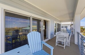 A balcony with a white table and chairs, a blue Adirondack chair, and a view of the ocean. - Ocean Views, Beach, Optional Heated Pool & Spa (Palm Coast)