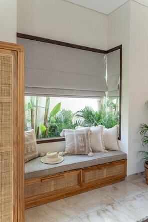 A room with a built-in bench, a large mirror, and a view of greenery outside. - Villa Athena One - Where Romance Meets Relaxation (Denpasar)