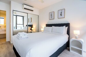 A hotel room with a large bed, a mirror, two bedside lamps, and framed artwork on the wall. - City-Center Cozy 2BDR Apartment with Parking (South Brisbane)