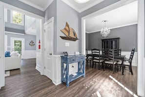 Ein geräumiges Zimmer mit Essbereich, einem weißen Sofa und einer Chandelüster.