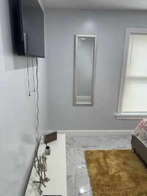Een moderne badkamer met een wit badkamermeubel, een grote spiegel en een raam met jaloezieën.