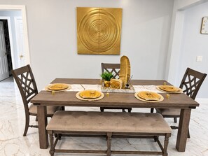 Ein Esstisch mit goldenem Geschirr, einer Bank und einem Wanddekor.