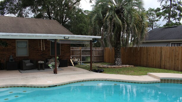 A backyard with a swimming pool, patio furniture, and a wooden fence. - Enjoyable 3-bedroom house with pool and AC in charming Jacksonville, Florida. (Jacksonville)