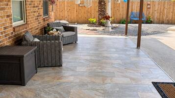 An outdoor patio with a brick wall, wicker furniture, and hanging decorations.