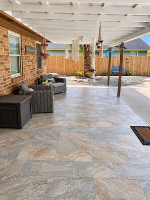 An outdoor patio with a brick wall, wicker furniture, and hanging decorations. - Enjoyable 3-bedroom house with pool and AC in charming Jacksonville, Florida. (Jacksonville)