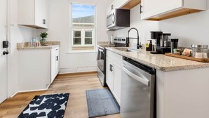 Una cocina moderna con gabinetes blancos, microondas integrado y cafetera.