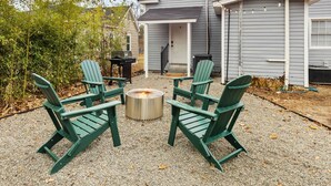 Un espacio al aire libre con cuatro sillas Adirondack dispuestas alrededor de una chimenea central.