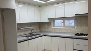 A modern kitchen with white cabinets, a stainless steel sink, and a window. - Happy house (Yongin-si)