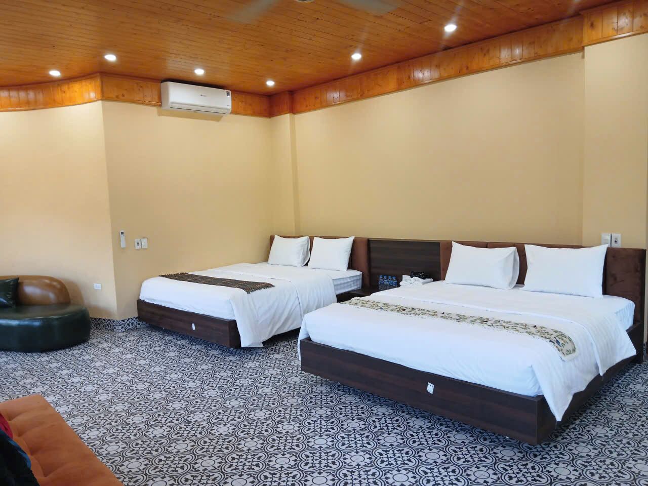 A hotel room with two beds, a sofa, and a patterned floor.
