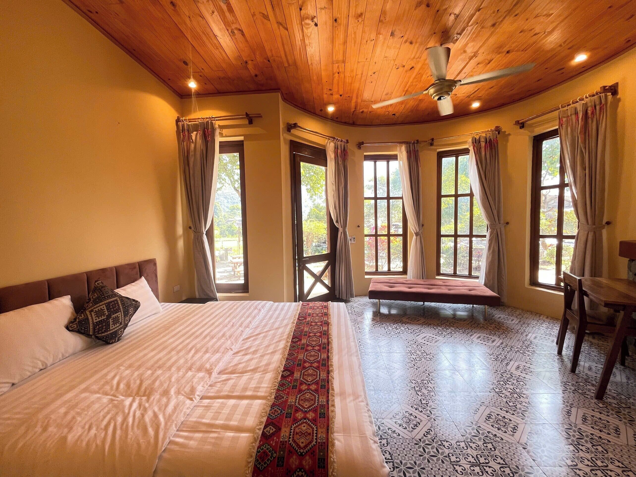A spacious bedroom with a large bed, a bench, and a ceiling fan.