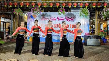A group of women performing a traditional dance in front of a banner with text and decorations.