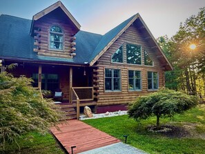 Une cabane en rondins avec une véranda, une terrasse et une cheminée en pierre.