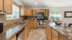 A kitchen with wooden cabinets, granite countertops, a microwave, an oven, and a sink. - Valley & Vine- Pool- Walking Distance to Old Town! (Scottsdale)