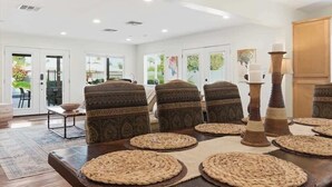 A dining area with a long table, patterned chairs, woven placemats, and tall candle holders. - Valley & Vine- Pool- Walking Distance to Old Town! (Scottsdale)