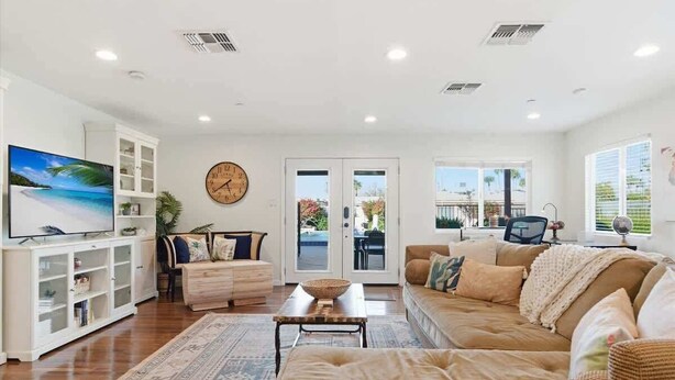 A living room with a TV, sofa, coffee table, and a view through the glass doors. - Valley & Vine- Pool- Walking Distance to Old Town! (Scottsdale)