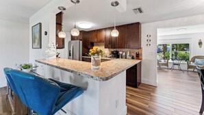 Una cucina moderna con piani in granito, elettrodomestici in acciaio inossidabile e luci a sospensione.