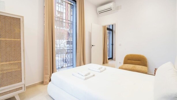 Ein Hotelzimmer mit Bett, Sessel, Kleiderschrank und Klimaanlage.