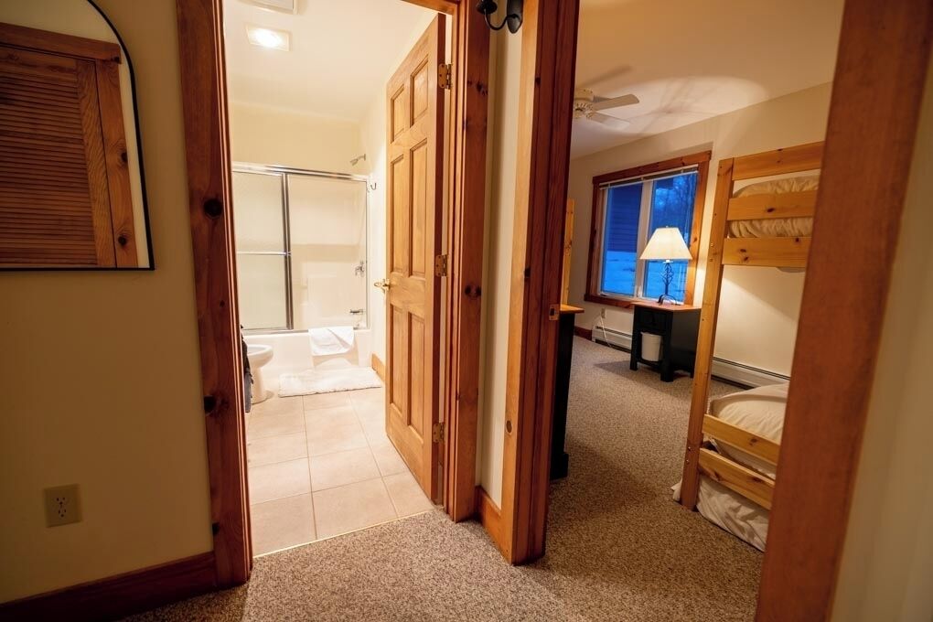 Ein Schlafzimmer mit Etagenbett, einem Fenster mit Blick und einem Badezimmer mit Dusche und Toilette.