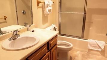 Une salle de bain avec un lavabo, un miroir et des toilettes.