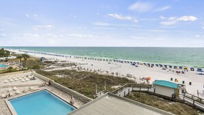 Un complexe hôtelier de bord de mer doté d’une piscine, de parasols et d’une tour de surveillance pour les sauveteurs.