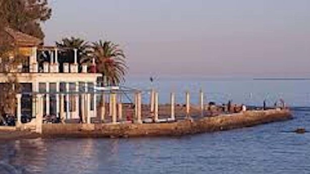A coastal building with a balcony overlooking the sea, a pier extending into the water, and a few people on the pier. - H2M Apartment Comfort in historic center (Distrito Centro)