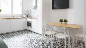 A modern kitchen with white cabinets, a wooden countertop, a built-in oven, and a black TV mounted on the wall. - Picasuss Loft Close Beach & Promenade (Málaga)