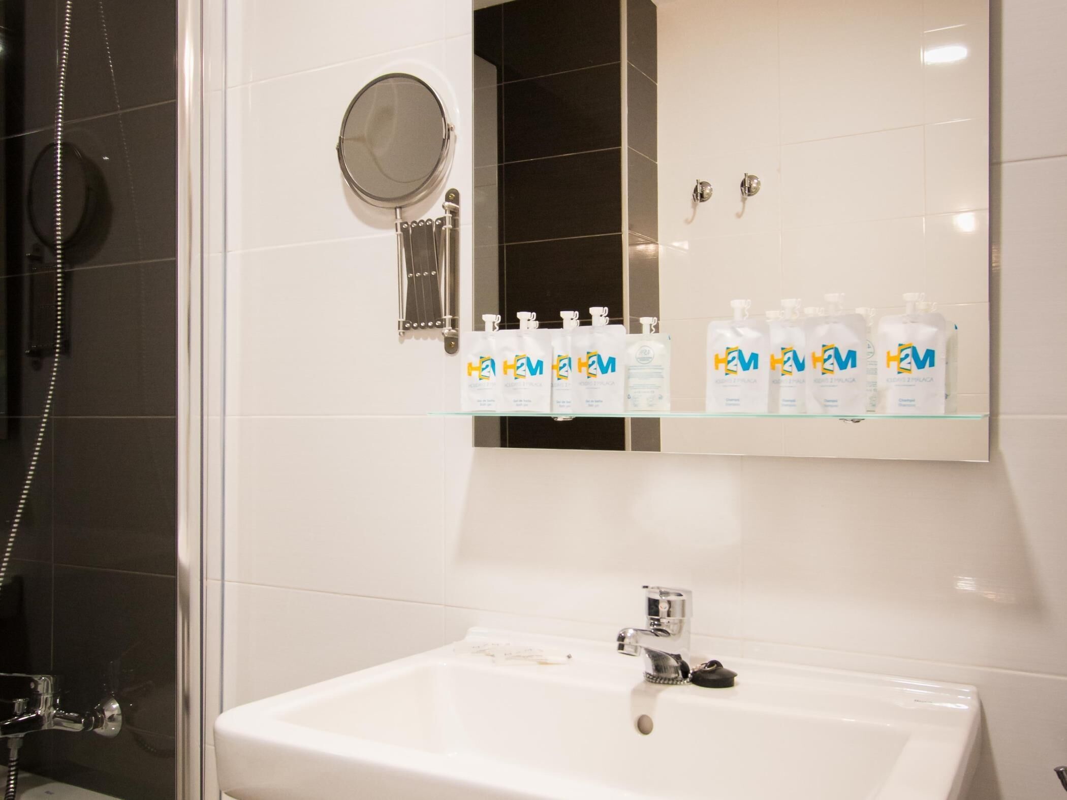 A bathroom with a white sink, a mirror, and shelves with H&M toiletries.
