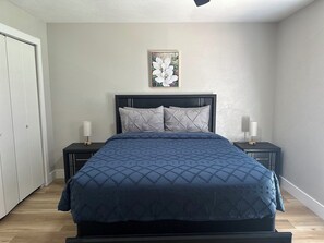 A bedroom with a bed, two bedside tables, a nightstand, a door, and a wall-mounted picture. - FIFA World cup, AT&T stadium, EPIC, Six flags! (Grand Prairie)