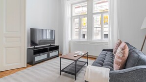 Ein modernes Wohnzimmer mit Fernseher, grauem Sofa und einem kleinen Tisch.
