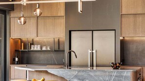 Een moderne keuken met een marmeren aanrechtblad, hanglampen en inbouwmeubels.