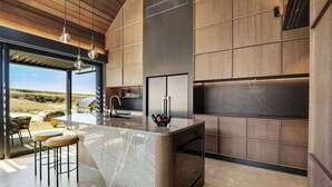 Een moderne keuken met een groot kookeiland, houten plafond en uitzicht op de omgeving.