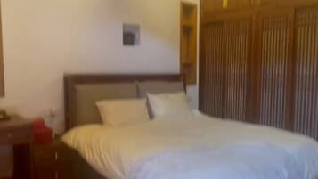 Un dormitorio con una cama grande, cabecera de madera, una mesita de noche y una mesilla.