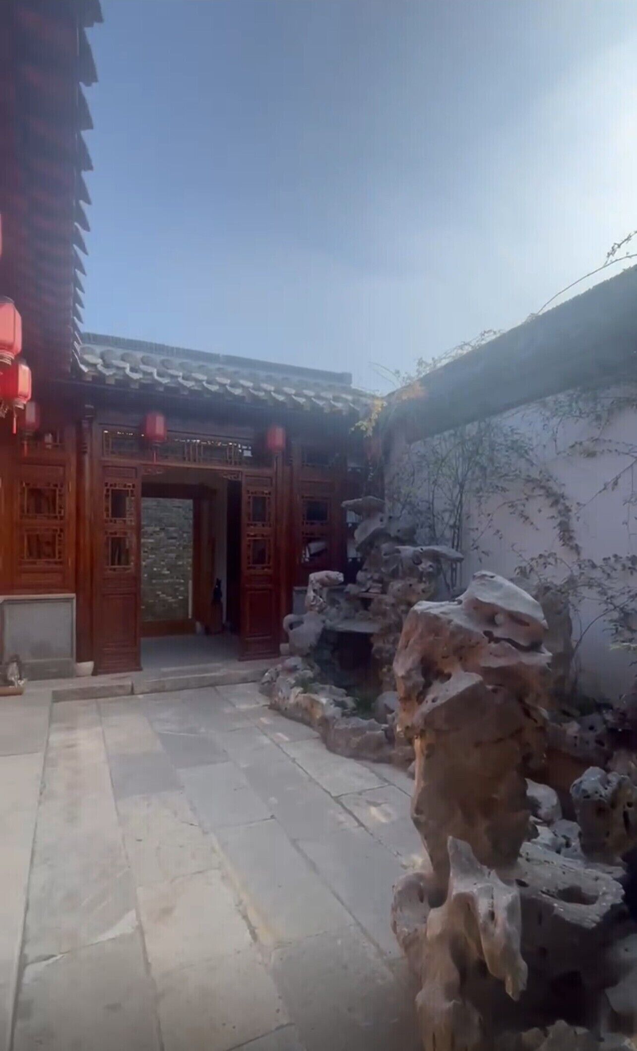 A traditional building with wooden architecture, a stone pathway, and a rock formation.