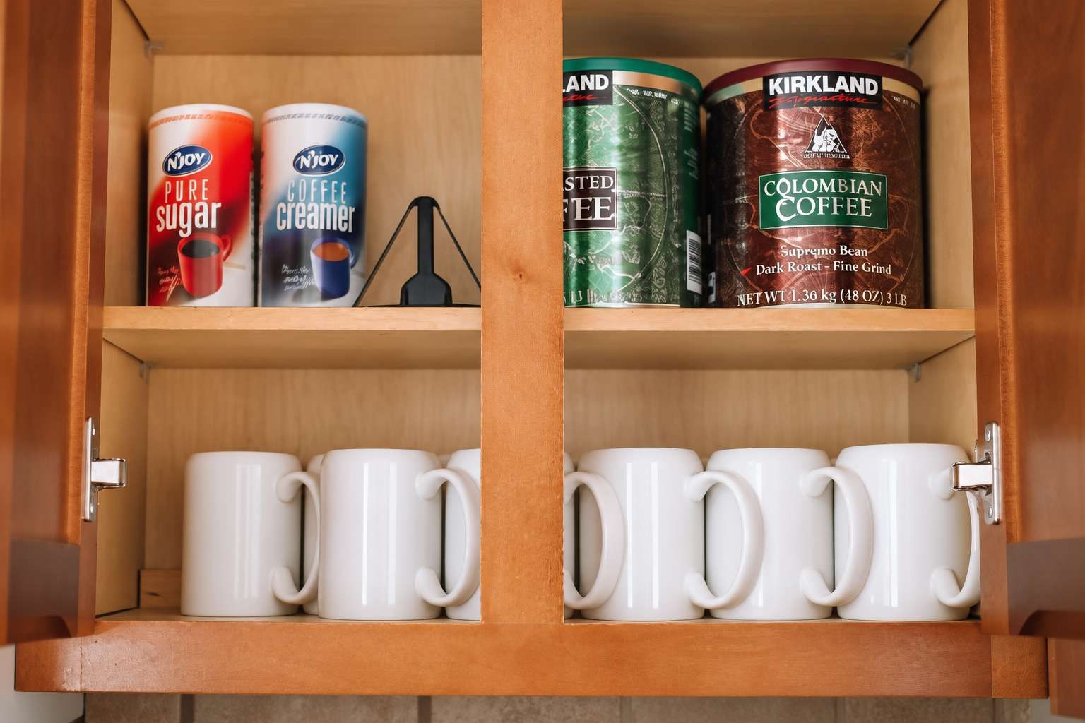 Um armário de madeira com três latas de leite condensado e dois grãos de café.