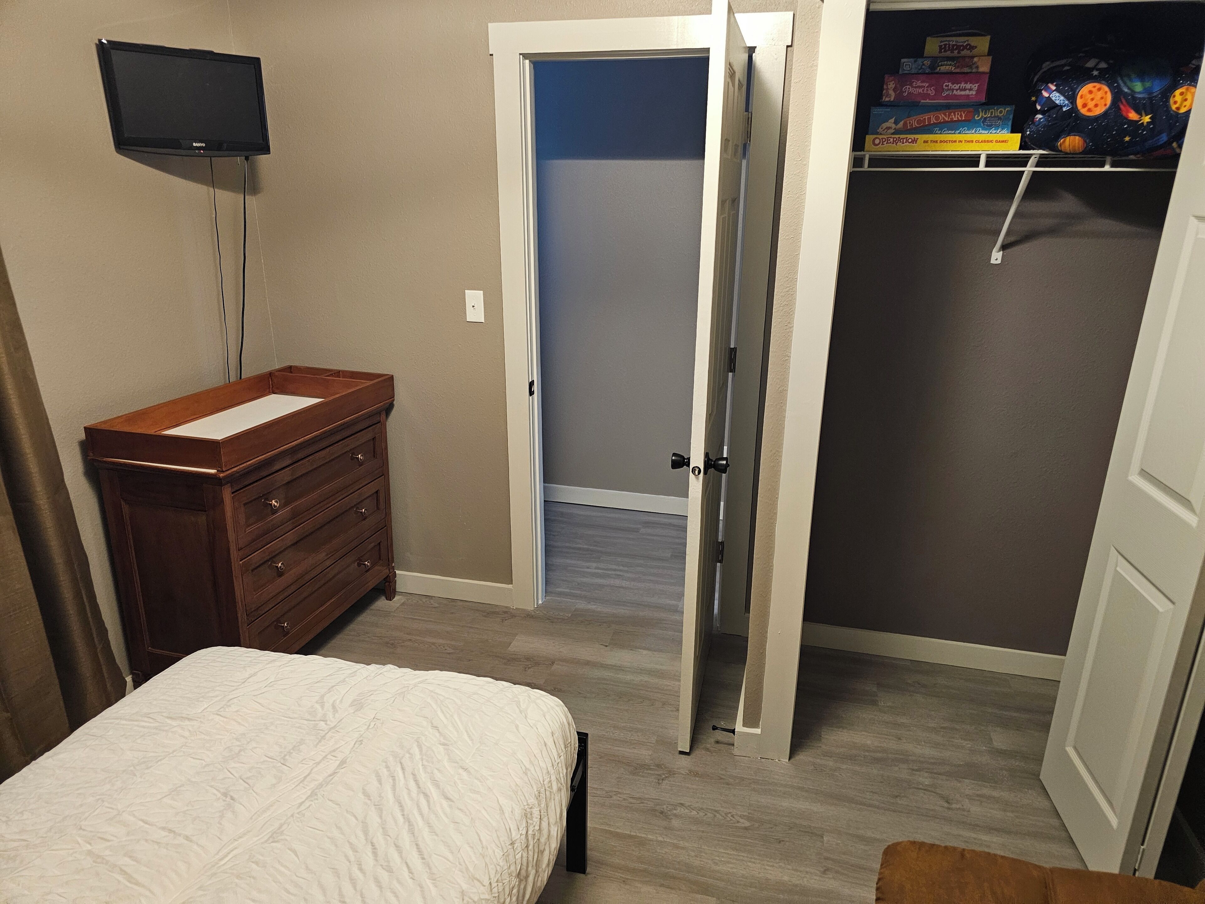 Une chambre à coucher avec un lit, une commode et un téléviseur fixé au mur.