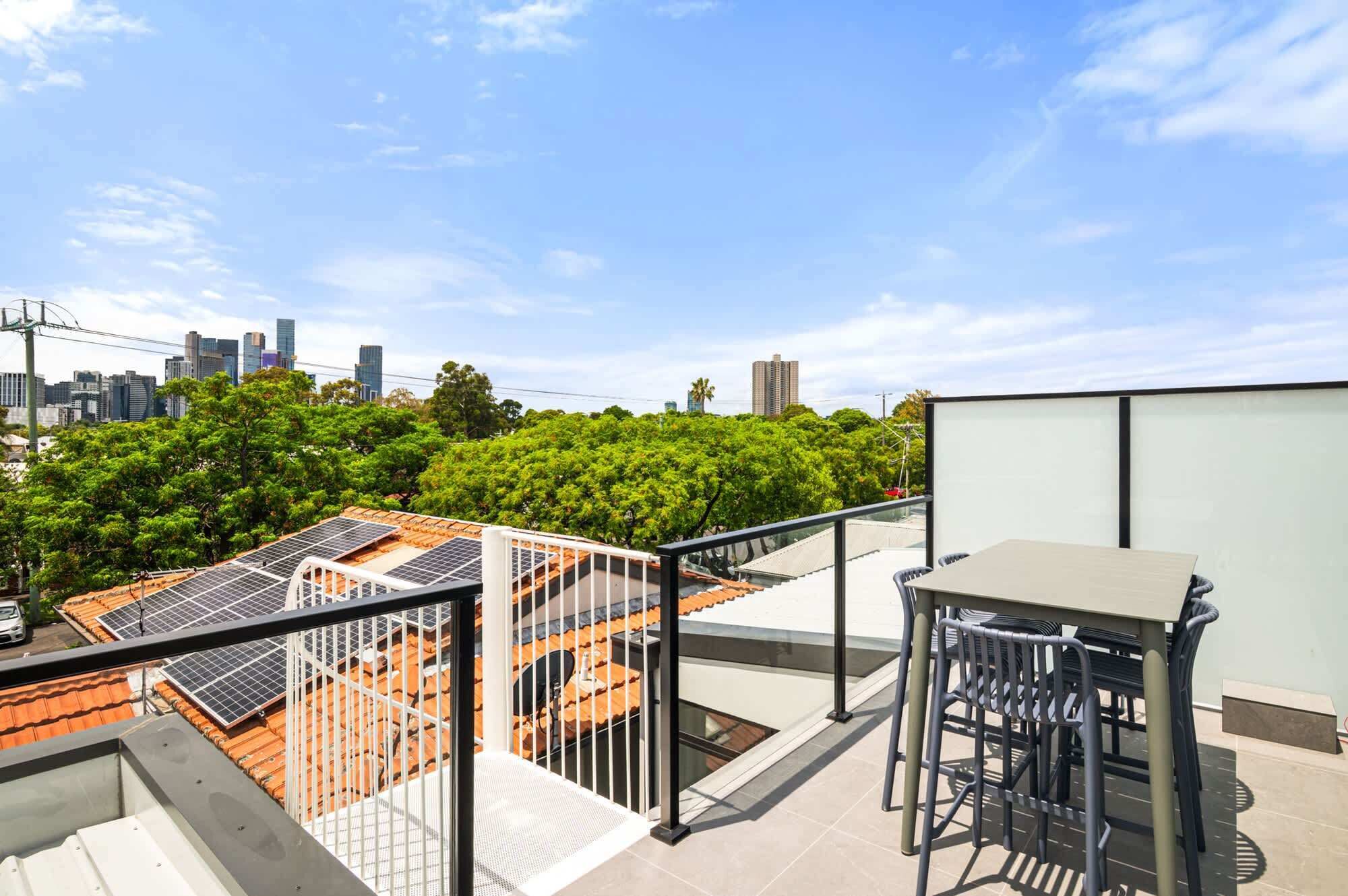 A rooftop terrace with solar panels, a table, and chairs.