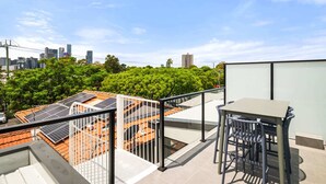 A rooftop terrace with solar panels, a table, and chairs. - Stylish 3-Bed Home Near South Melbourne Market (South Melbourne)