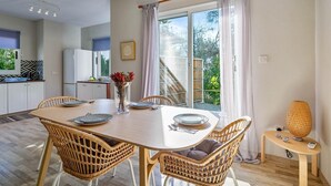A dining area with a wooden table, wicker chairs, and a vase with flowers. - Villa Eva Breeze by Ezoria Villas (Coral Bay)