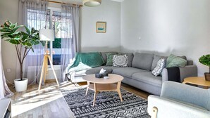A modern living room with a grey sofa, a round coffee table, a standing lamp, and a large potted plant. - Villa Eva Breeze by Ezoria Villas (Coral Bay)