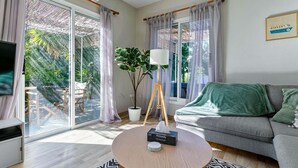 A modern living room with a grey sofa, a round coffee table with a tissue box, a floor lamp, and a TV on the left. - Villa Eva Breeze by Ezoria Villas (Coral Bay)