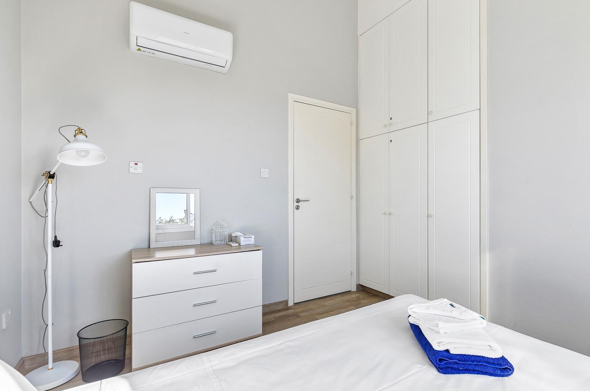 Une chambre à coucher comprenant un lit, une table de chevet avec une lampe, une commode, une fenêtre donnant sur un paysage agréable et une armoire.