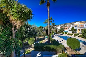 A resort with a swimming pool, palm trees, and Mediterranean-style buildings. - Villa Eva Breeze by Ezoria Villas (Coral Bay)