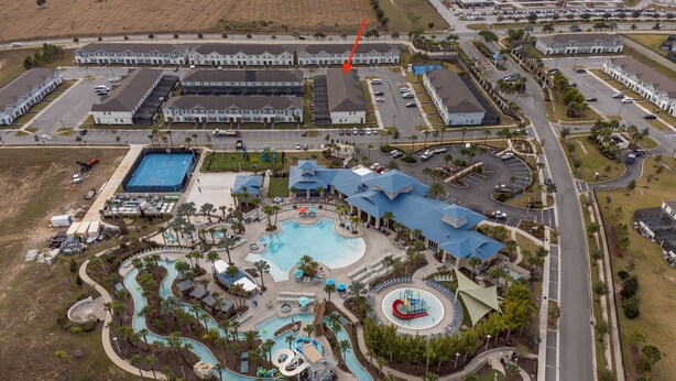 Vista aérea de un resort con una piscina grande, toboganes acuáticos y un campo de golf.