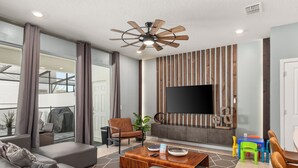 Una sala de estar moderna con un sofá, una mesa de centro y un televisor montado en la pared sobre una chimenea.