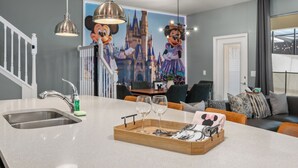 Una cocina con una isla grande, un lavamanos de acero inoxidable y luces colgantes.