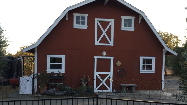 A red barn with white trim, a single door, and two windows. - Cozy 1-bedroom studio barn cottage in tranquil Winters (Winters)